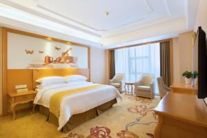 una camera d'albergo con un grande letto e una scrivania di Vienna International Hotel Changsha Hongxing a Changsha