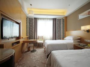 a hotel room with two beds and a flat screen tv at Vienna Hotel Waigaoqiao in Shanghai