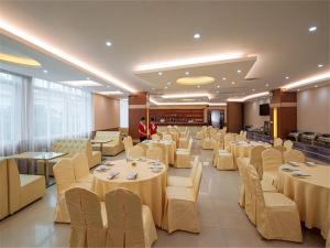 um salão de banquetes com mesas e cadeiras e uma pessoa em Vienna Hotel Guangzhou Dongpu Bus Station em Guangzhou