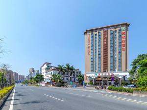 una calle vacía con un gran edificio a un lado de la carretera en Vienna Hotel Shenzhen Henggang New City, en Longgang
