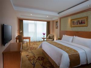 a hotel room with a large bed and a television at Vienna International Hotel Shenzhen Longgang Lilang in Longgang