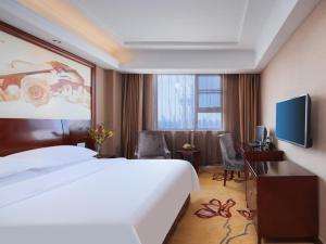 a hotel room with a large bed and a flat screen tv at Vienna Hotel Nanchang Ruzi Road in Nanchang