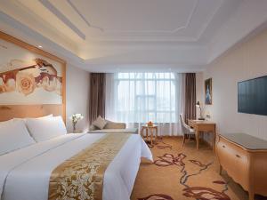 ein Hotelzimmer mit einem großen Bett und einem Schreibtisch in der Unterkunft vienna Hotel (fujian quanzhou dehua station) in Dehua