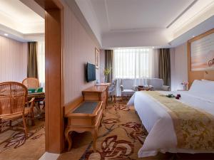Vienna Hotel Huizhou Baiyun Road في هويزو: غرفة الفندق بسرير كبير ومكتب