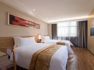 a hotel room with two beds and a television at Vienna 3 Best Hotel Shenzhen Pinghu Fumin Road in Longgang +2 photos