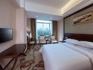 a hotel room with a large bed and a television at Vienna Hotel Guangzhou Shaheding Metro Station in Guangzhou