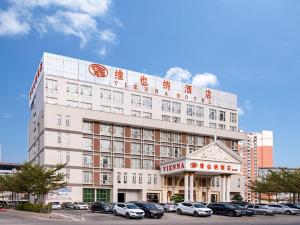 a hotel with cars parked in a parking lot at Vienna Hotel Guangdong Gaozhou City East Passenger Depot in Gaozhou