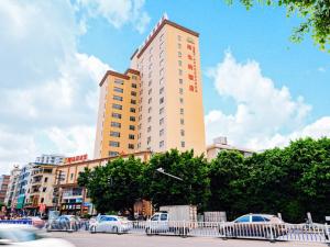 a tall building with cars parked in front of it at Vienna Hotel Huizhou Huiyang Danshui Road in Huizhou
