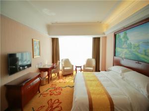 a hotel room with a large bed and a desk at Vienna International Hotel Shandong Weihai Rongcheng in Rencheng