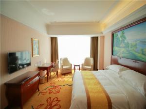 a hotel room with a large bed and a desk at Vienna International Hotel Shandong Weihai Rongcheng in Rongcheng