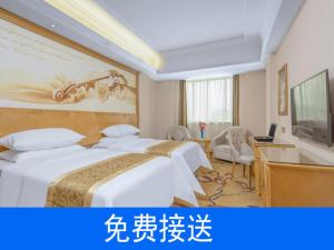 a hotel room with two beds and a desk at Vienna Hotel Guangzhou South Railway Station in Guangzhou