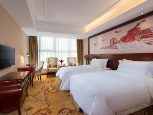 a hotel room with two beds and a television at Vienna Hotel Shenzhen Shuiku New Village in Shenzhen