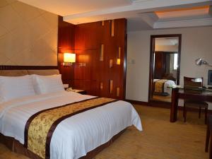 een hotelkamer met een groot bed en een bureau bij Vienna International Hotel Dongguan Changping Swan Lake Road in Dongguan