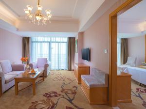 Vienna Hotel Huizhou Baiyun Road في هويزو: غرفة في الفندق مع غرفة معيشة مع سرير وأريكة