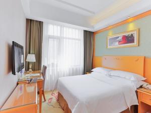 a hotel room with a bed and a desk and a television at Vienna Hotel Tianjin Huanghe Road in Tianjin