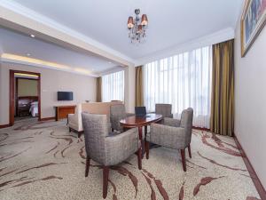 una habitación de hotel con mesa y sillas en Vienna International Hotel Xiangyang Railway Station en Xiangyang