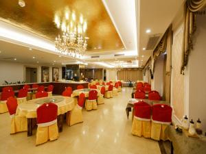 a restaurant with tables and red chairs and a chandelier at Vienna Hotel Shaoguan Wuli Pavilion in Shaoguan