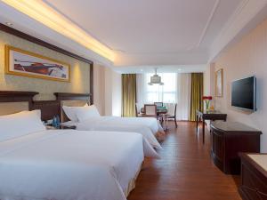 a hotel room with two beds and a television at Vienna 3 Best Hotel Guangzhou Zengcheng Xintang Harbour Avenue in Zengcheng