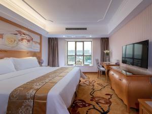 een hotelkamer met een groot bed en een televisie bij Vienna Hotel Nanning Gaoxin District in Nanning