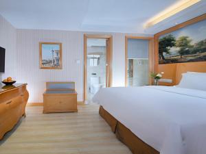 una camera con un grande letto bianco e un bagno di Vienna Hotel Dongguan Tangxia Garden Street a Tangxia