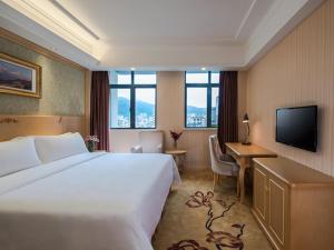 深セン市にあるVienna Hotel Shenzhen East Railway Stationのベッド、デスク、テレビが備わるホテルルームです。