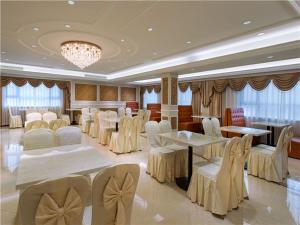 un salón de banquetes con mesas blancas y sillas blancas en Vienna International Hotel (Shen Zhen Buji Dafen shop), en Shenzhen
