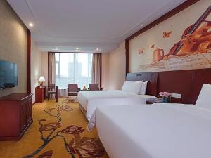 NanhaiにあるVienna International Hotel Guangzhou Jiaokou Subway Stationのベッド2台と薄型テレビ付きのホテルの部屋