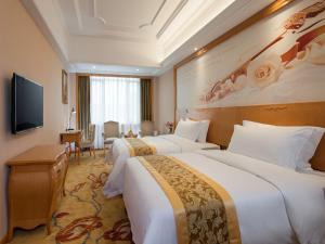 Cette chambre comprend 2 lits et une télévision à écran plat. dans l'établissement Vienna International Hotel Guangzhou Airport Xinshi, à Canton