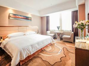 a bedroom with a large bed and a living room at Vienna International Hotel Huhan Jiedaokou in Wuhan