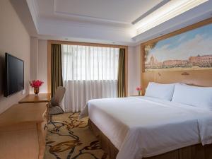 a hotel room with a large bed and a window at Vienna International Hotel Guangzhou Xintang Jean Fangzhicheng in Zengcheng +8 photos
