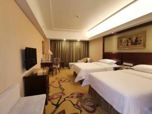FenyiにあるVienna Hotel Xinyu Fenyi South Changshan Roadのベッド3台とテレビが備わるホテルルームです。