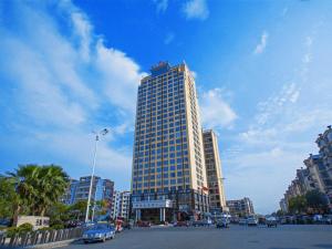 wysoki budynek z samochodami zaparkowanymi przed nim w obiekcie Vienna Hotel Jiangxi Yichun City Hall w mieście Yichun