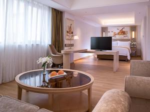 a large hotel room with a bed and a living room at Vienna International Hotel (Changfeng Park Shop, Jinshajiang Road, Shanghai) in Shanghai