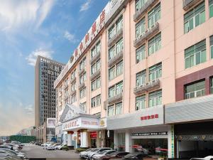a large pink building with cars parked in a parking lot at Vienna Hotel Shenzhen BaoAn Qianjin Road in Bao'an