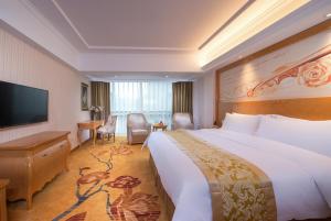 a hotel room with a large bed and a flat screen tv at Vienna Hotel Guangdong Zhongshan Tanzhou in Zhongshan +7 photos