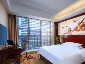 sypialnia z dużym łóżkiem i dużym oknem w obiekcie Vienna Hotel Nanchang Ruzi Road w mieście Nanchang