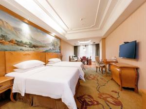 a hotel room with two beds and a flat screen tv at Vienna International Hotel Zhuzhou Railway Station Central Plaza in Zhuzhou