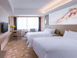 a hotel room with two beds and a television at Vienna Hotel Shenzhen Pingji Ave in Longgang