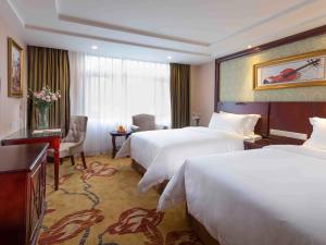 a hotel room with two beds and a desk at Vienna Hotel Guangzhou Jinshazhou in Nanhai