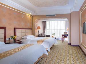una camera d'albergo con tre letti e una televisione di Vienna Hotel Songgang Yanchuan Road a Bao'an