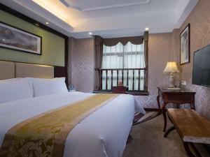 ein Hotelzimmer mit einem großen Bett und einem Fenster in der Unterkunft Vienna 3 Best Hotel Meizhou Mei County People Square in Meizhou
