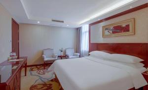 a bedroom with a large white bed and two chairs at Vienna Hotel Changsha Mid Furong Road in Changsha +2 photos