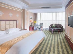 una camera d'albergo con un grande letto e una TV di Vienna Hotel Songgang Yanchuan Road a Bao'an