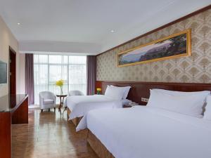 una camera d'albergo con due letti e una televisione di Vienna Hotel Shiqiao Metro Station a Canton