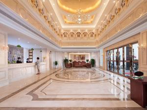 a large lobby with a man standing in the middle of a building at Vienna Hotel Huizhou Baiyun Road in Huizhou