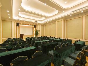 une salle de conférence avec des chaises vertes et un écran dans l'établissement Vienna International Hotel Changsha Hongxing, à Changsha