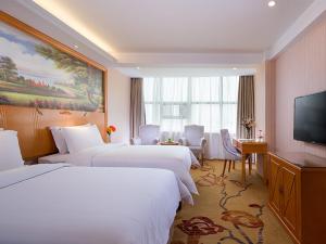 a hotel room with three beds and a flat screen tv at Vienna Hotel(Changshu Sitir Store) in Zhangshu