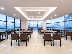 ein Restaurant mit Tischen und Stühlen und großen Fenstern in der Unterkunft Vienna Hotel Shenzhen Songgang Shajiang Road in Bao'an