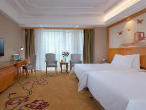 una camera d'albergo con un letto grande e una scrivania di Vienna International Hotel (Fangchenggang Administration Center High-speed Railway Station branch) a Fangcheng