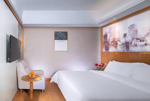 Vienna 3 Best Hotel (Ganzhou shangyou store) في Yuanzicha: غرفة نوم بسرير ابيض كبير وطاولة